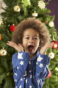 Excited Young Boy In Front Of Christmas Tree