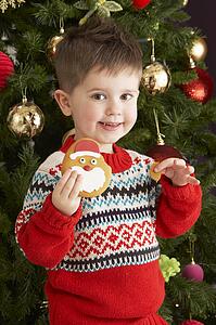 Young Boy Eating Cookie In Front Of Christmas Tree