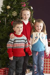 Group Of Young Children With Presents In Front Of Christmas Tree