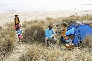Young Family Relaxing On Beach Camping Holiday