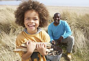 Father And Son Collecting Firewood On Beach Camping Holiday