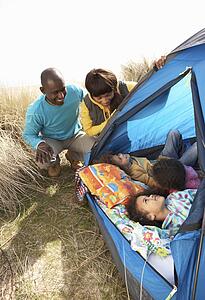 Young Family Relaxing Inside Tent On Camping Holiday