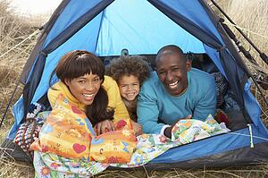 Young Family Relaxing Inside Tent On Camping Holiday