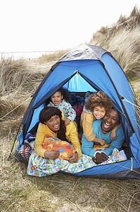 Young Family Relaxing Inside Tent On Camping Holiday