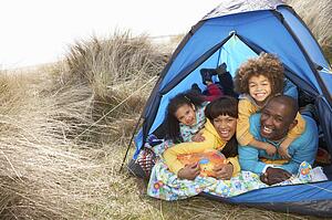 Young Family Relaxing Inside Tent On Camping Holiday
