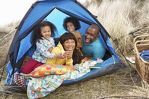 Young Family Relaxing Inside Tent On Camping Holiday