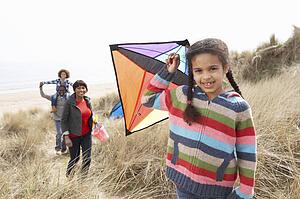 Family Having Fun With Kite In Sand Dunes