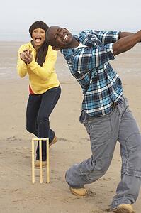 Young Couple Playing Cricket On Autumn Beach Holiday