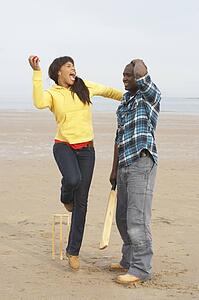 Young Couple Playing Cricket On Autumn Beach Holiday