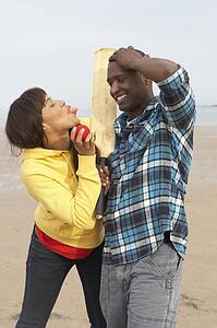 Young Couple Playing Cricket On Autumn Beach Holiday