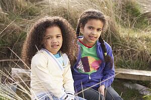 Young Girls Playing In Field Together