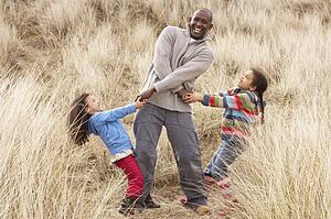 Father And Daughters Having Fun In Sand Dunes