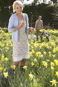 Woman Hiding Decorated Easter Eggs For Hunt Amongst Daffodils