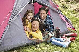 Young Family Relaxing Inside Tent On Camping Holiday
