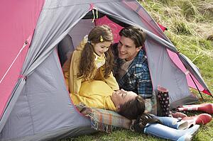 Young Family Relaxing Inside Tent On Camping Holiday
