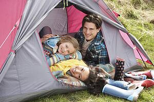 Young Family Relaxing Inside Tent On Camping Holiday