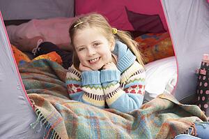 Young Girl Relaxing Inside Tent On Camping Holiday