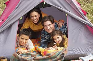 Young Family Relaxing Inside Tent On Camping Holiday