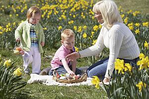 Mother And Children In Daffodil Field With Decorated Easter Eggs