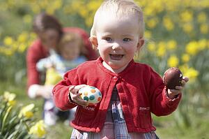 Mother And Children In Daffodil Field With Decorated Easter Eggs