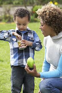 Mother Helping Son To Unwrap Chocolate Easter Egg