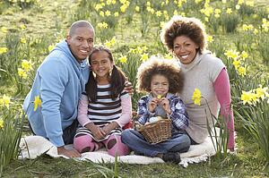 Family Relaxing In Field Of Spring Daffodils