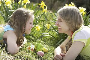Mother And Daughter On Easter Egg Hunt In Daffodil Field
