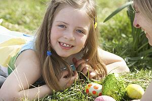 Mother And Daughter On Easter Egg Hunt In Daffodil Field