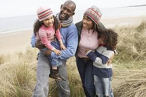 Family Walking Along Dunes On Winter Beach