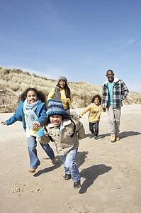 Family Running On Winter Beach