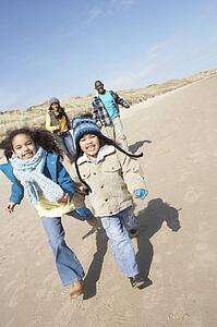 Family Running On Winter Beach