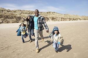 Family Running On Winter Beach