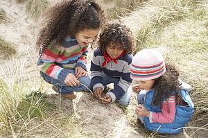 Children Playing In Dunes On Winter Beach