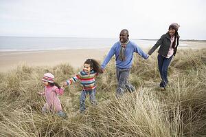 Family Walking Along Dunes On Winter Beach