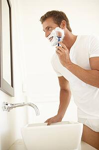 Young Man Shaving In Bathroom Mirror
