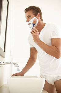 Young Man Shaving In Bathroom Mirror