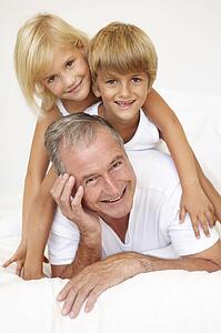 Grandfather Relaxing On Bed With Grandchildren