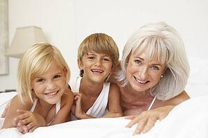 Grandmother Relaxing On Bed With Grandchildren