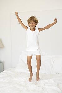 Young Boy Jumping On Bed