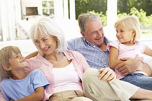 Portrait Of Grandparents With Grandchildren Relaxing Together On Sofa