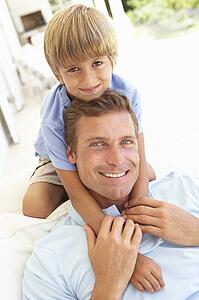 Portrait Of Father And Son Relaxing On Sofa