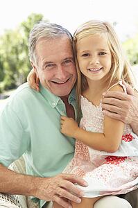 Portrait Of Grandfather With Granddaughter Relaxing Together On Sofa