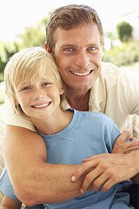 Portrait Of Father And Son Relaxing On Sofa
