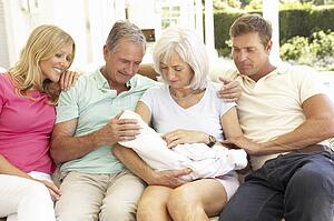 Extended Family Relaxing Together On Sofa With Newborn Baby