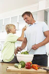 Father & Son Preparing Salad In Modern Kitchen
