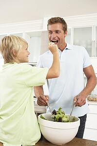 Father & Son Preparing Salad In Modern Kitchen
