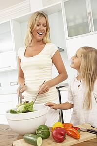 Mother & Daughter Preparing Salad In Modern Kitchen