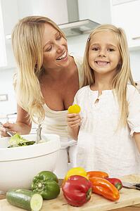 Mother & Daughter Preparing Salad In Modern Kitchen