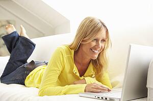 Woman Using Laptop Relaxing Sitting On Sofa At Home