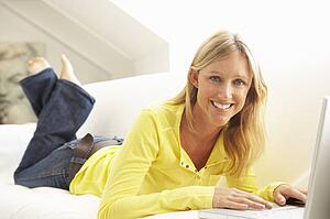Woman Using Laptop Relaxing Sitting On Sofa At Home